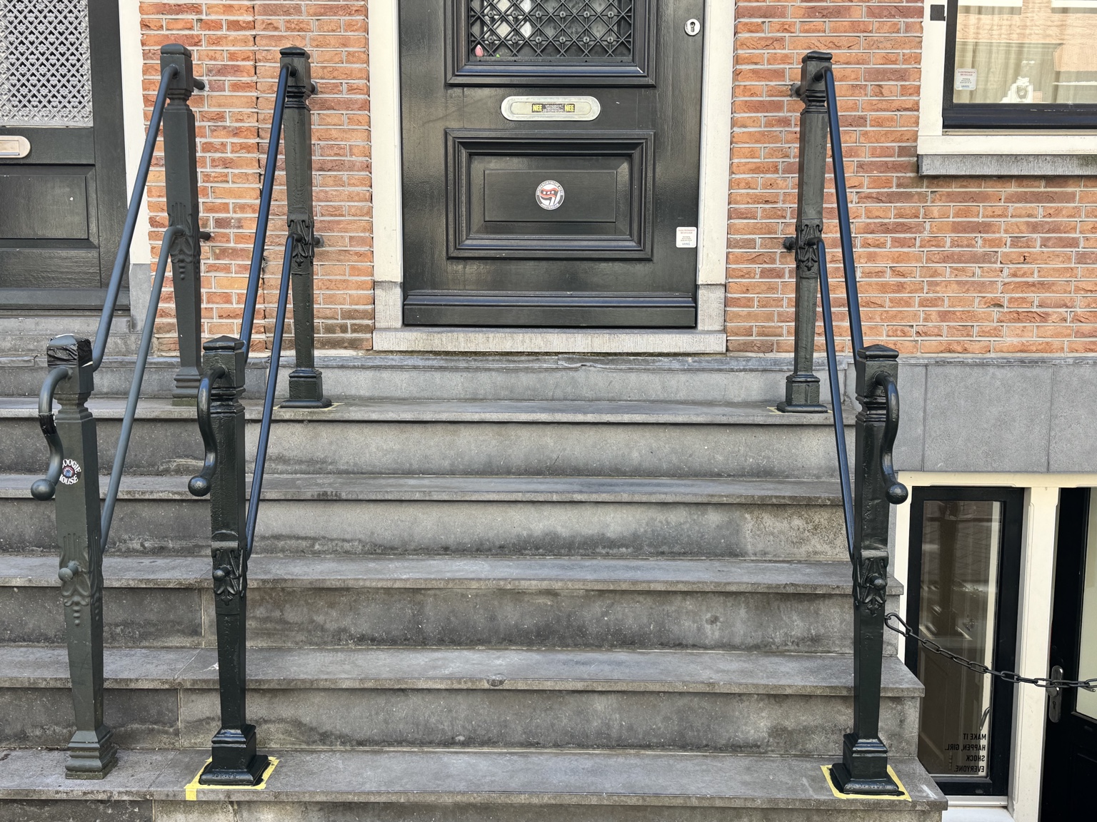 Donkere metalen leuningen langs de stenen entreetrap aan de Lange Leidsedwarsstraat in Amsterdam
